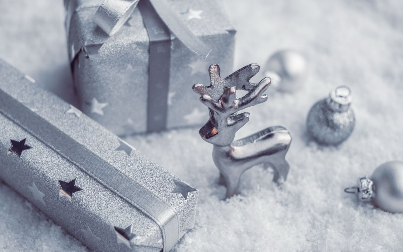 Cadeaux de Noël argentés et renne décoratif posés sur la neige