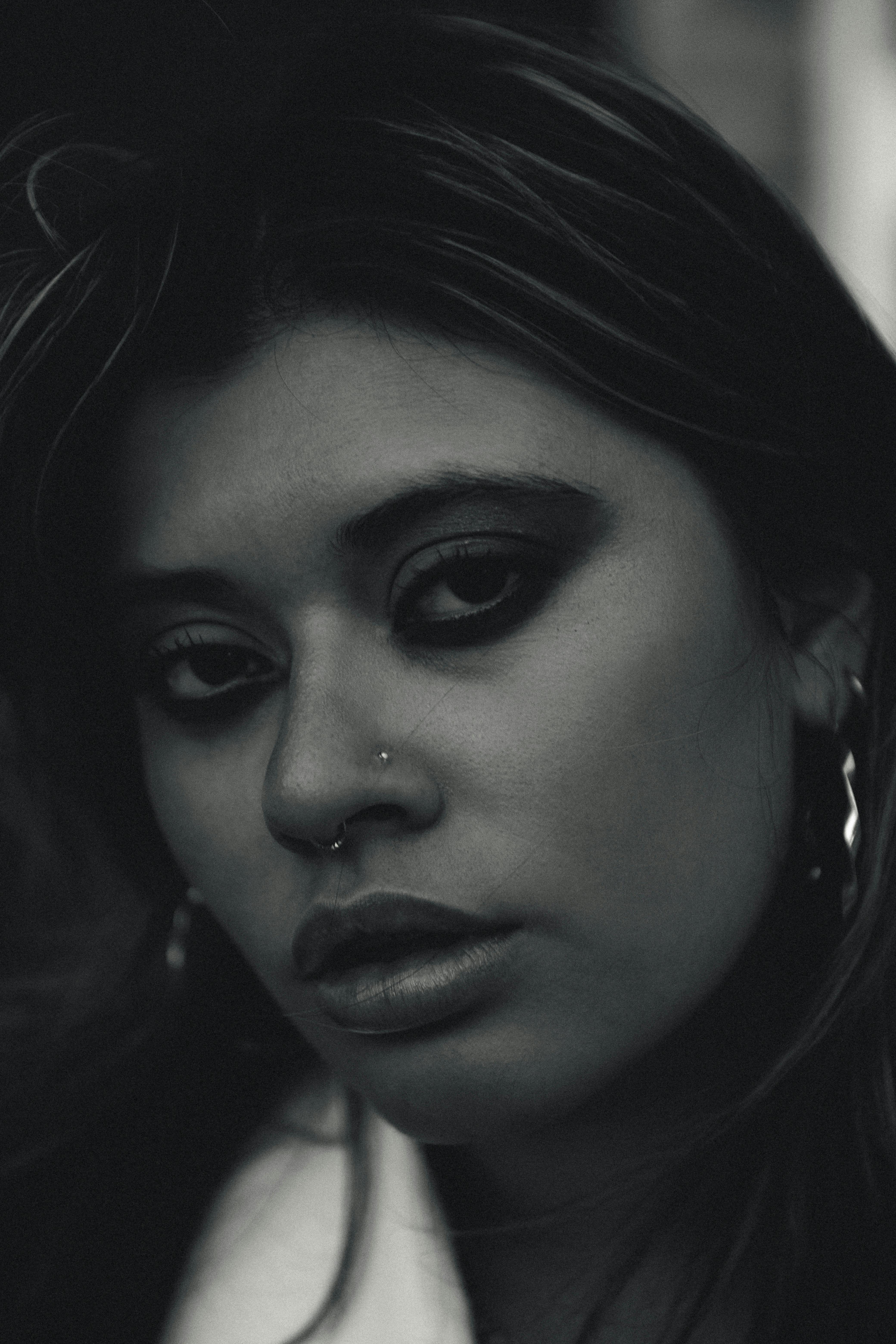 Portrait noir et blanc d'une femme avec piercing au nez et septum, regard intense.