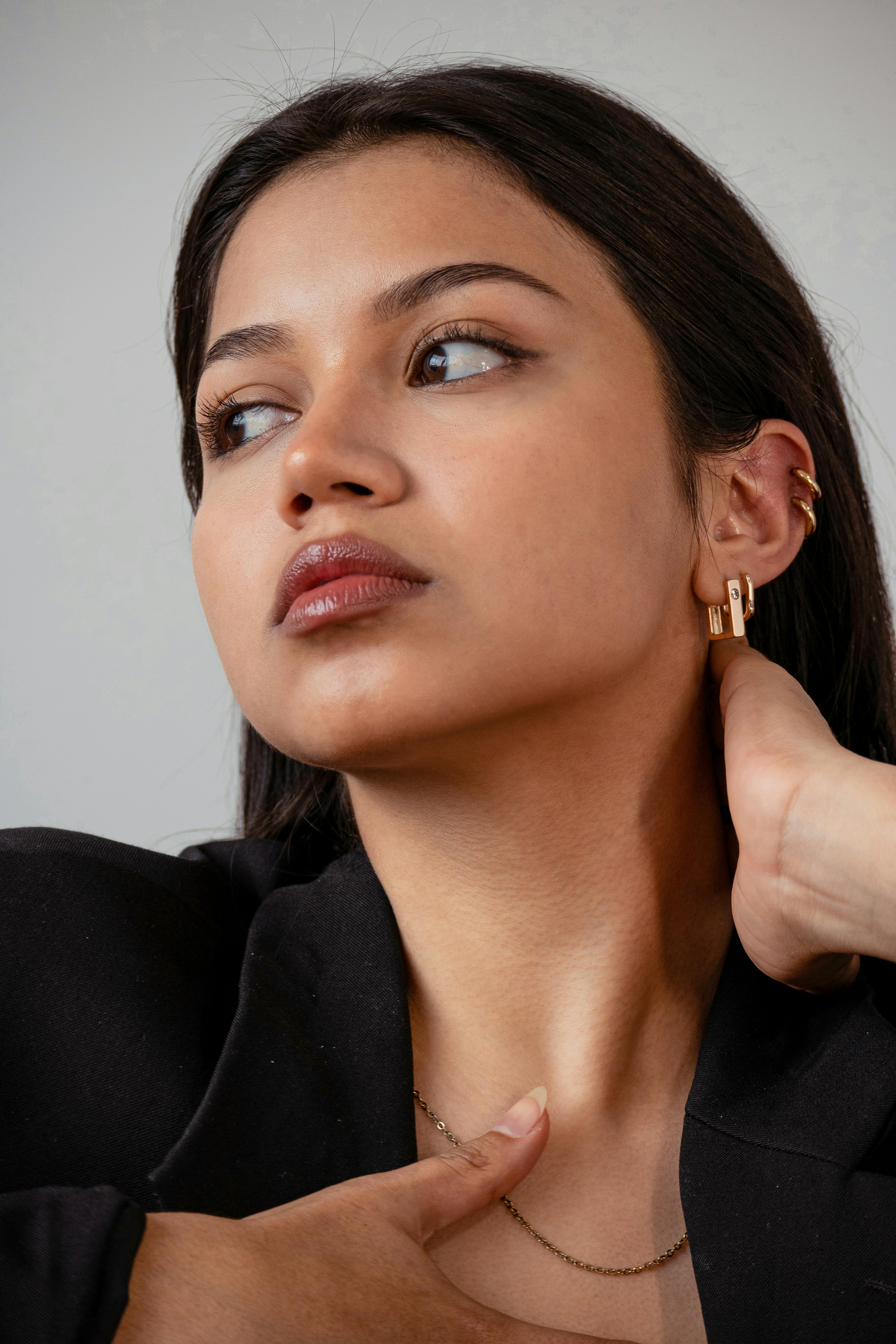 Woman's ear adorned with several gold ear cuffs and delicate earrings.
