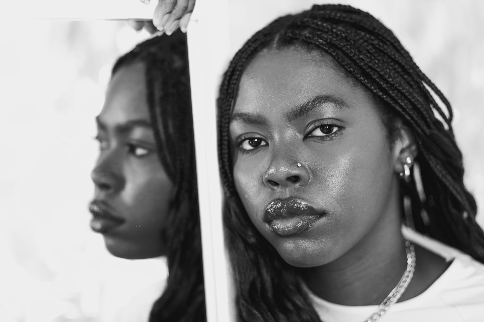Black and white portrait of a woman with braids wearing a small nostril stud