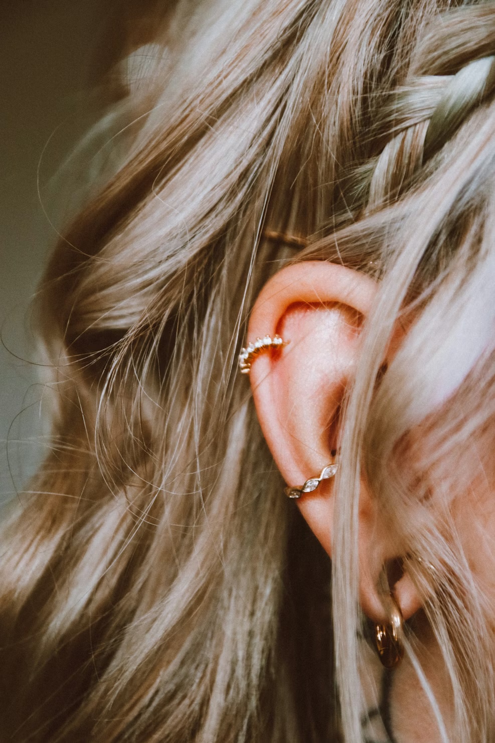 Female ear with a helix piercing featuring a gold piece and other cartilage piercings